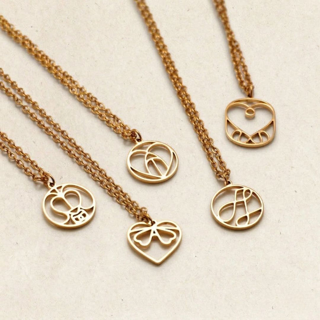 JUNE ELLE personalized monogram necklace designs in various shapes laid out on a neutral background