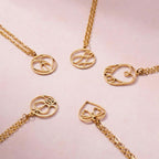 JUNE ELLE gold monogram necklace with letter-formed designs in round, oval and heart shapes arranged in a circle
