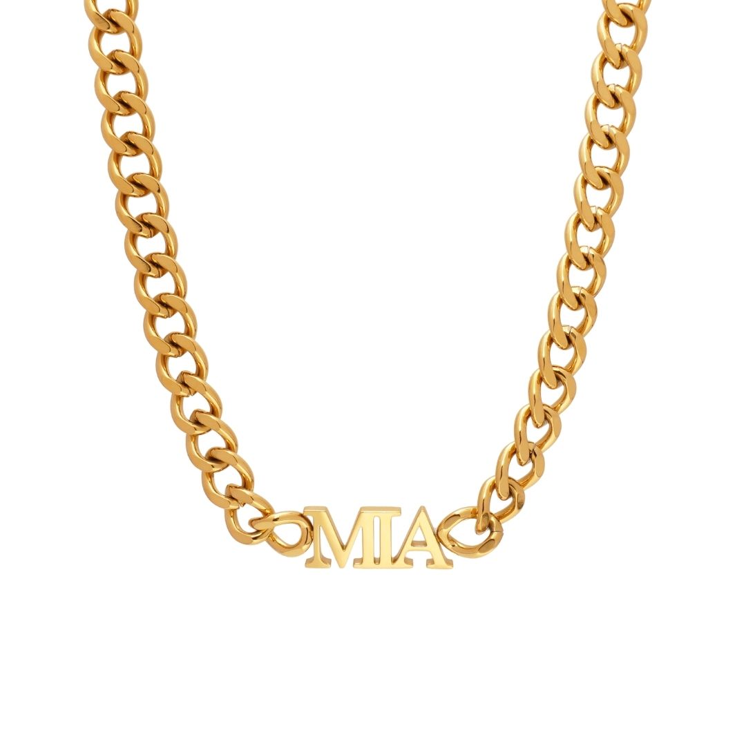 A JUNE ELLE chunky gold-tone curb chain necklace with a personalized horizontal "MIA" pendant in a classic serif font, shown against a white background.