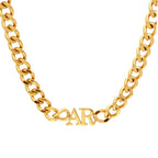 A JUNE ELLE chunky gold-tone curb chain necklace with a personalized horizontal "AR" pendant in a classic serif font, shown against a white background.