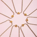 JUNE ELLE gold initial tennis bracelets featuring letters A to G arranged in a circular layout close-up detail view on pink background