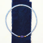 JUNE ELLE MagMix Modular Blue Chalcedony Bead Necklace with interchangeable Lapis Lazuli Barrel Centerpiece, stylized overhead flat lay with modular connections on indigo linen and white background