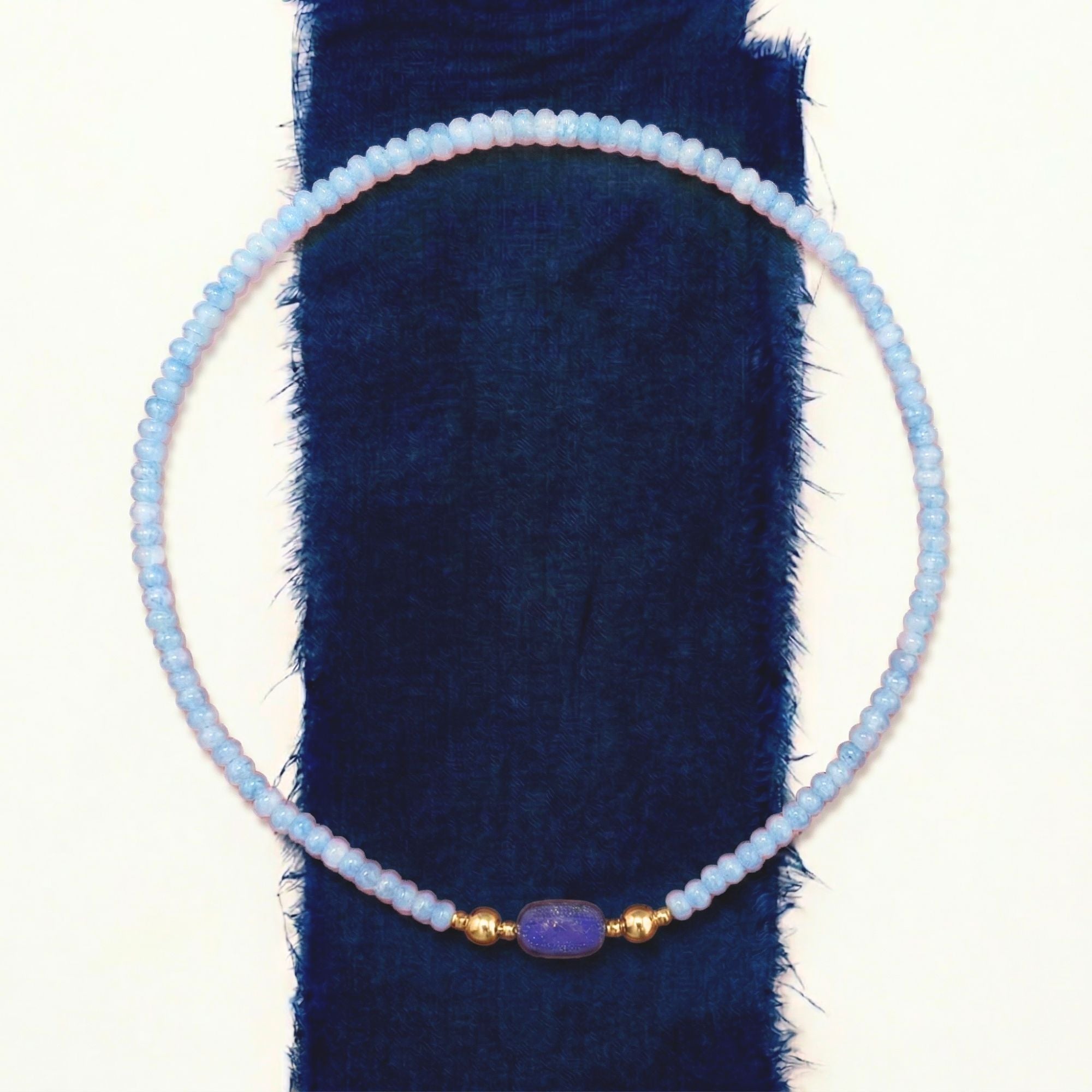 JUNE ELLE MagMix Modular Blue Chalcedony Bead Necklace with interchangeable Lapis Lazuli Barrel Centerpiece, stylized overhead flat lay with modular connections on indigo linen and white background