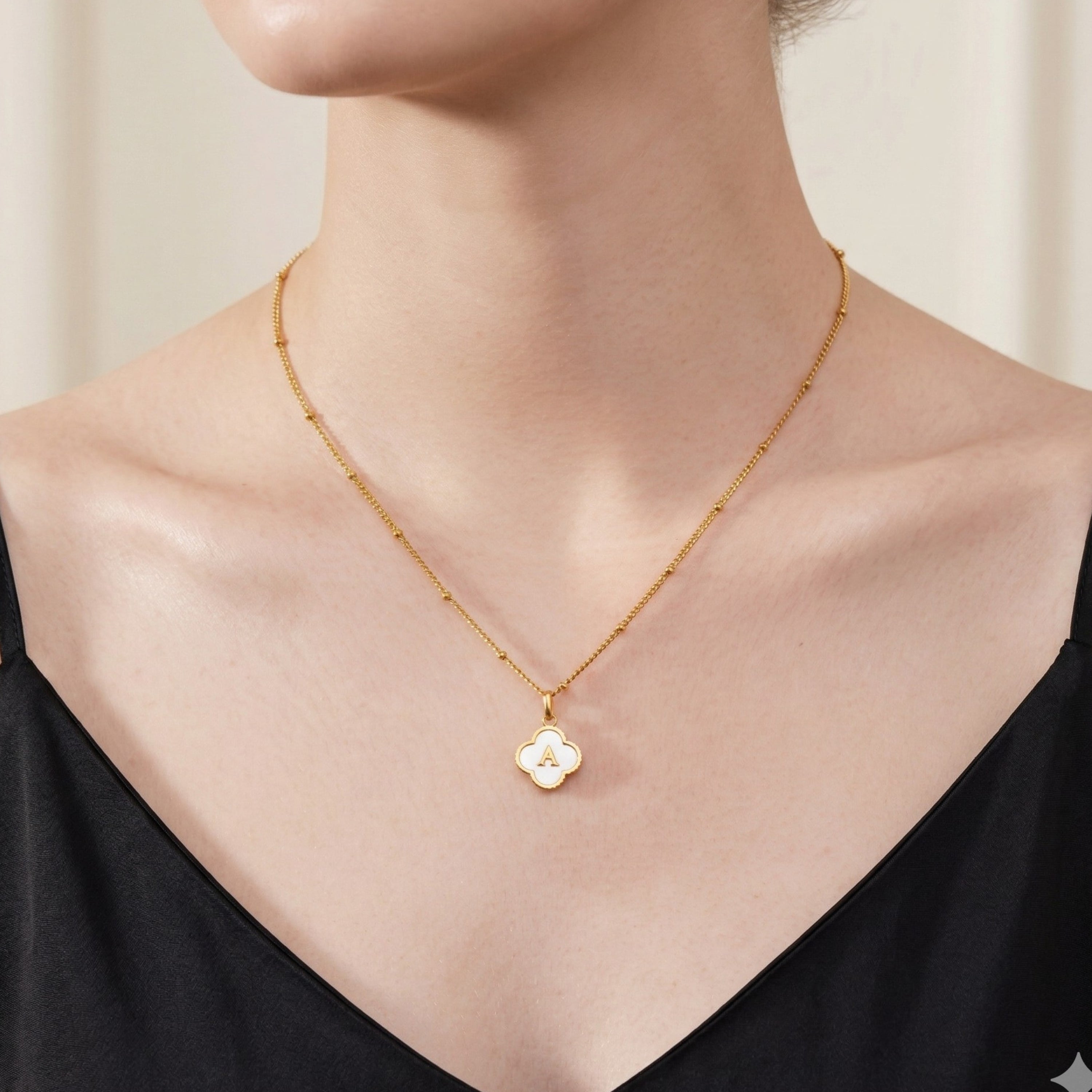 JUNE ELLE gold mother-of-pearl clover initial charm letter A on sphere chain necklace worn on model front view, customizable A to Z