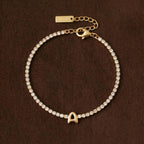 JUNE ELLE gold initial tennis bracelet with letter A arranged in a perfect circle on chocolate fabric background front view