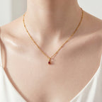 Model wearing UNE ELLE gold heart birthstone charm necklace in 18K gold plated finish