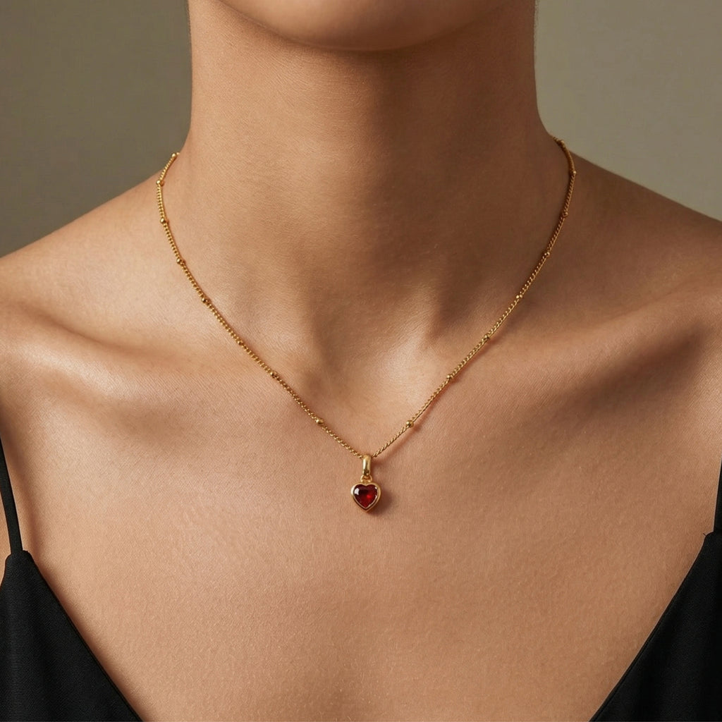 Close-up of JUNE ELLE gold heart birthstone charm necklace resting on the model