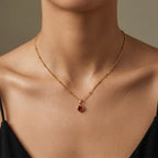 Close-up of JUNE ELLE gold heart birthstone charm necklace resting on the model