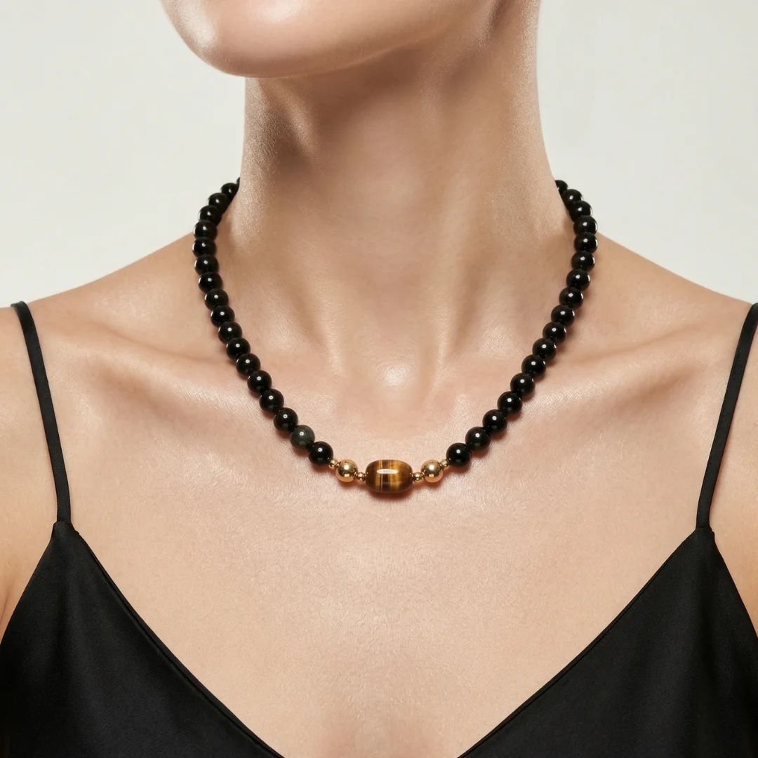 Model wearing the JUNE ELLE MagMix interchangeable necklace, combining a black obsidian bead base chain with a Tiger’s Eye barrel centerpiece connected by gold magnetic clasps.
