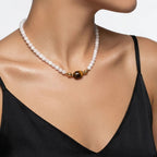Close-up on model's neckline wearing the JUNE ELLE MagMix interchangeable jewelry, highlighting a Tiger’s Eye barrel focal piece connected to a soft pink Rose Quartz beaded chain via gold magnetic clasps.