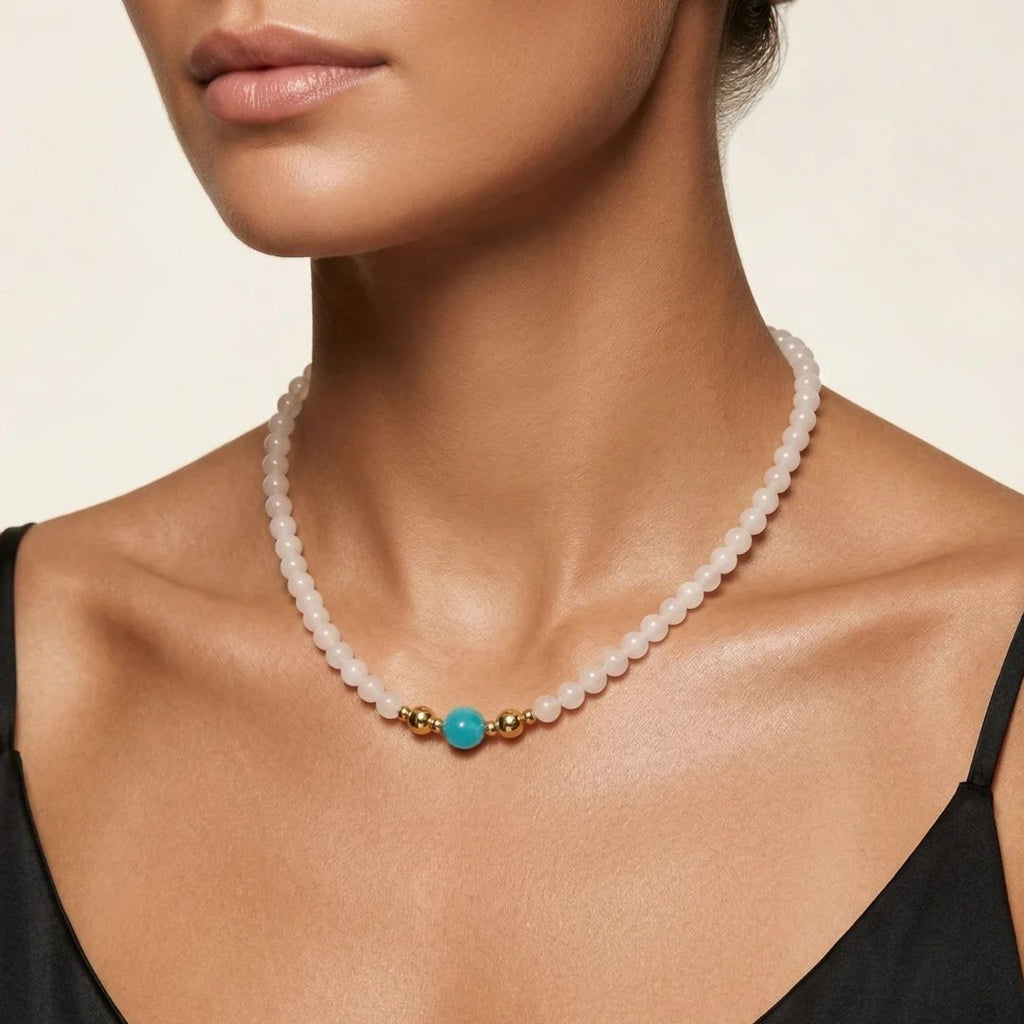 Close-up on model's collarbone showcasing the JUNE ELLE MagMix interchangeable jewelry, blending a white chalcedony bead necklace with a vibrant Amazonite center bead connected by gold magnetic clasps.