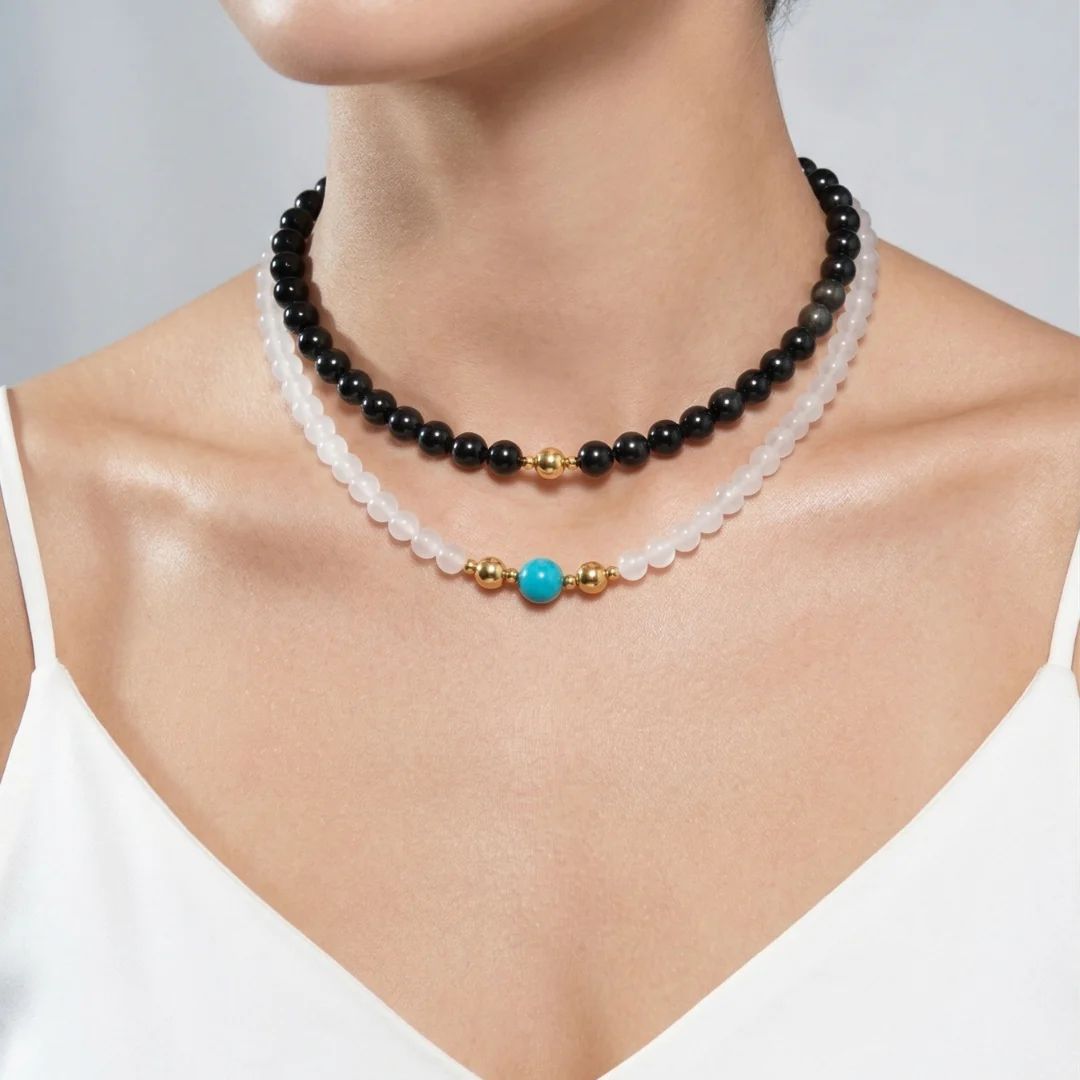 Model wearing a layered stack of JUNE ELLE MagMix interchangeable necklaces, pairing a black Obsidian bead choker with a white Chalcedony base chain and an Amazonite centerpiece attached by gold magnetic clasps.