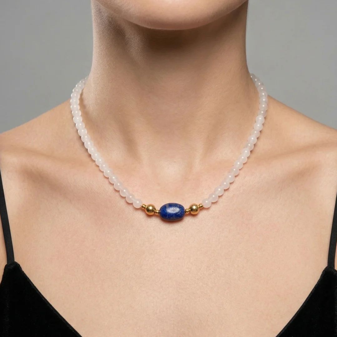 Model wearing the JUNE ELLE MagMix interchangeable necklace, combining a soft white chalcedony bead chain with a lapis lazuli barrel centerpiece connected by gold magnetic clasps.